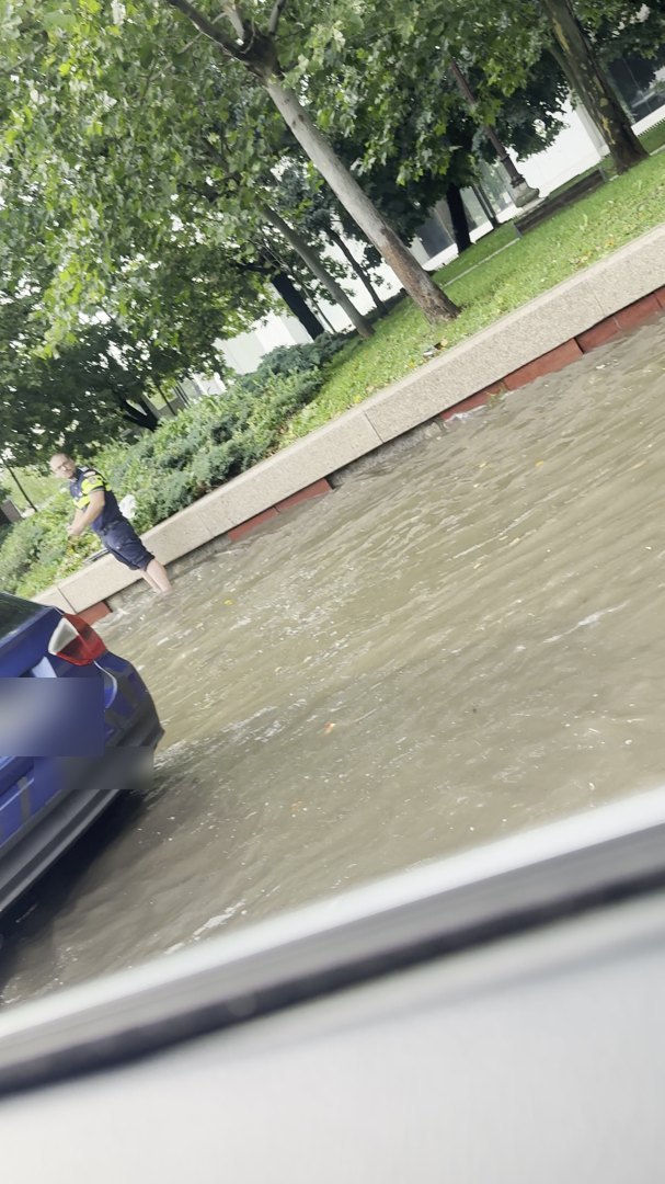 Polițist cu pantalonii suflecați lângă o gură de canalizare în timpul inundațiilor din București, 19 iulie 2026
